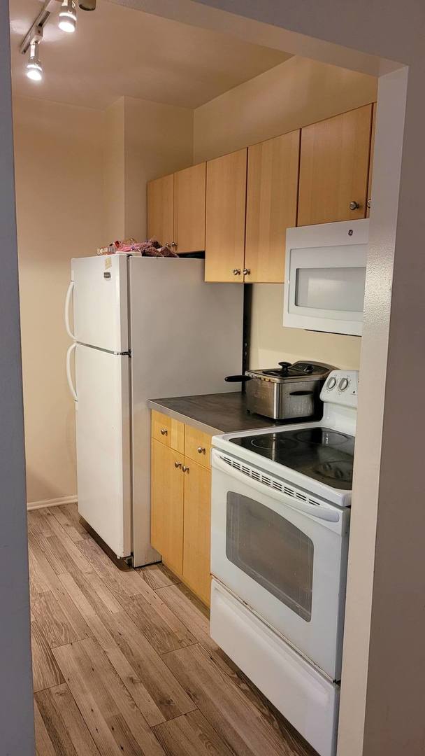 kitchen featuring white appliances, light hardwood / wood-style floors, track lighting, and light brown cabinets