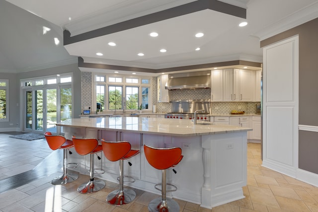 kitchen featuring crown molding, a spacious island, ventilation hood, and light stone countertops