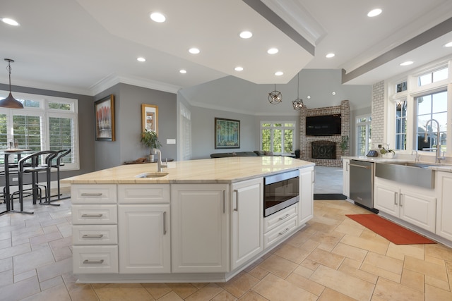 kitchen featuring a fireplace, decorative light fixtures, stainless steel appliances, and sink