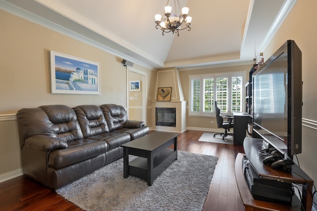 living room featuring a large fireplace, dark hardwood / wood-style floors, an inviting chandelier, and ornamental molding