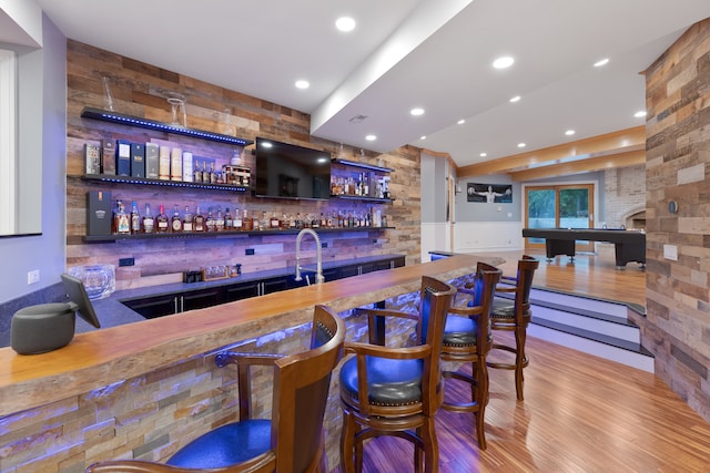 bar featuring tasteful backsplash, hardwood / wood-style flooring, and sink