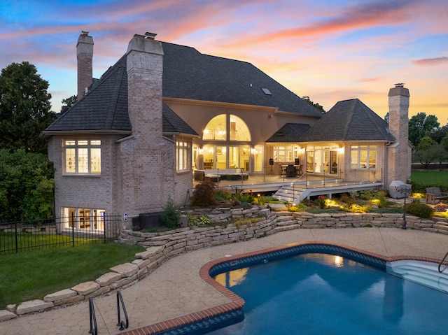 pool at dusk featuring a yard and a patio