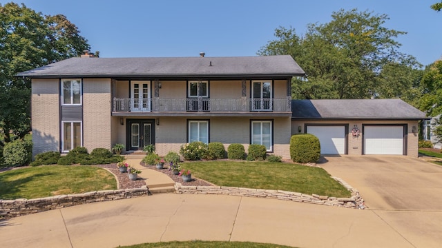 view of front of property featuring a garage, a balcony, a front yard, and french doors