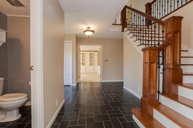 stairway featuring visible vents, baseboards, and stone finish flooring