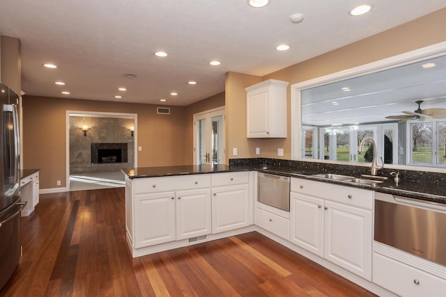 kitchen with a tile fireplace, white cabinetry, sink, dark wood-type flooring, and kitchen peninsula