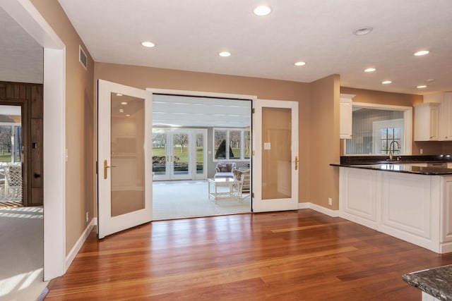 kitchen with white cabinetry, wood finished floors, dark countertops, and french doors