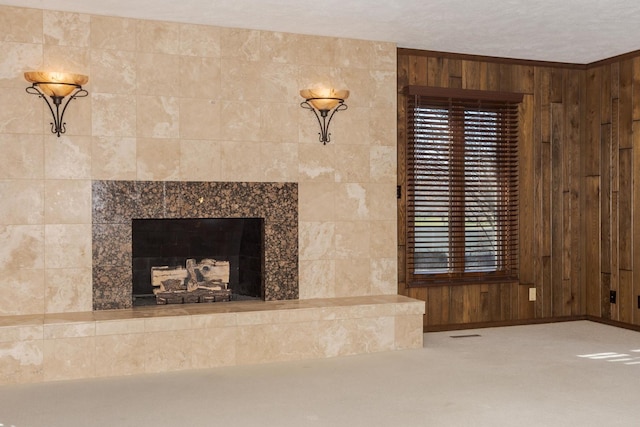 room details with carpet flooring, wood walls, ornamental molding, and a tiled fireplace