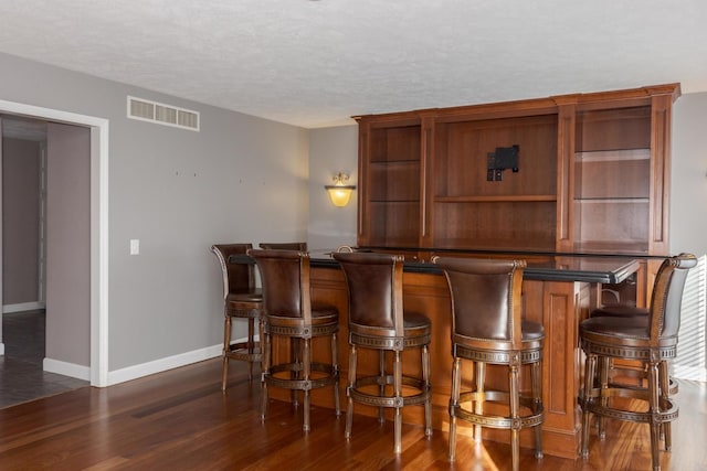 bar with visible vents, baseboards, dark wood finished floors, and a dry bar