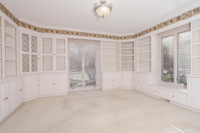 carpeted empty room featuring built in features, visible vents, and ornamental molding