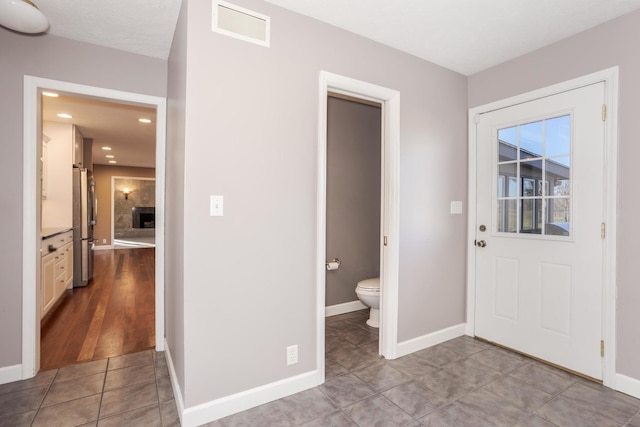 bathroom featuring a fireplace, tile patterned flooring, and toilet