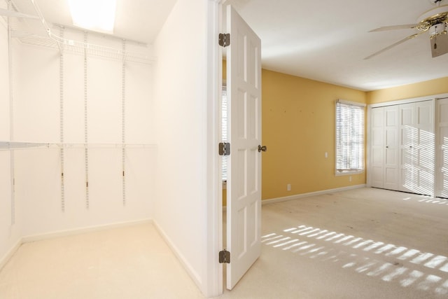 walk in closet with ceiling fan and light colored carpet