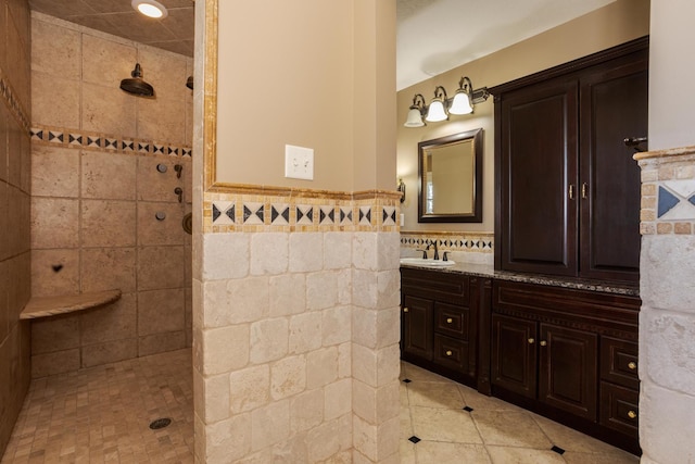 bathroom featuring tile walls, walk in shower, wainscoting, and vanity