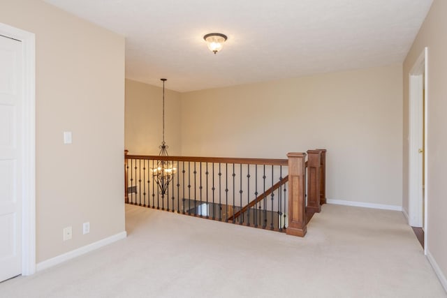 hallway with baseboards, an upstairs landing, and a chandelier