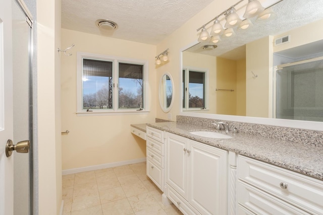 bathroom with a shower with door, vanity, and a textured ceiling