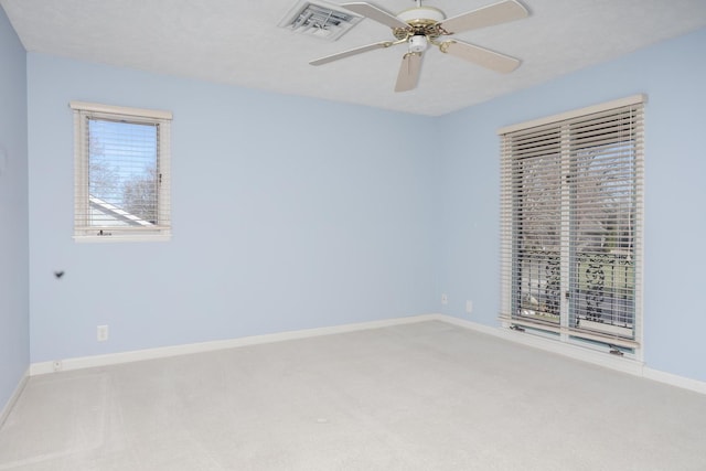 carpeted spare room featuring visible vents, a ceiling fan, and baseboards