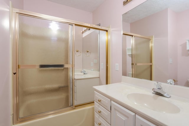 bathroom with vanity, bath / shower combo with glass door, and a textured ceiling