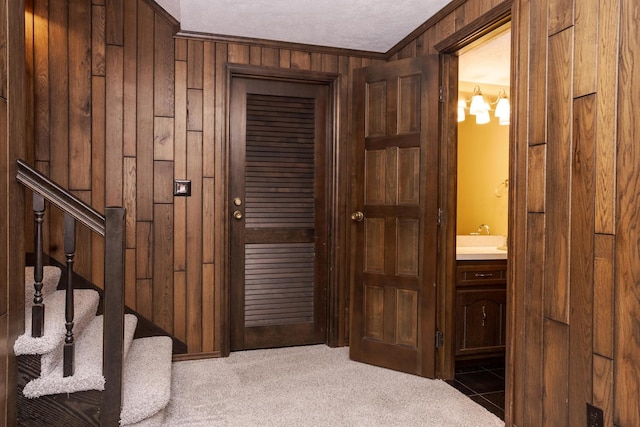 interior space featuring stairs, wood walls, carpet flooring, and ornamental molding