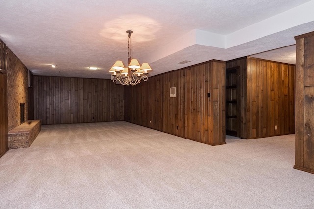 interior space with light carpet, a brick fireplace, a notable chandelier, and wood walls