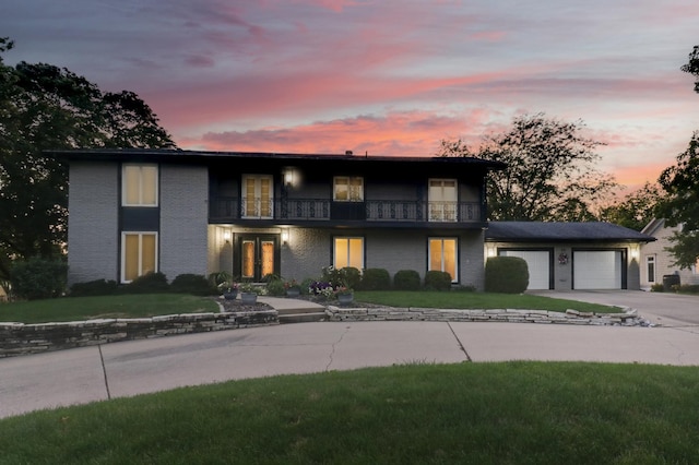 view of front of property featuring a balcony, french doors, concrete driveway, an attached garage, and brick siding