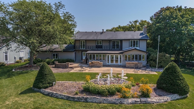 rear view of house featuring a patio, a yard, and a chimney