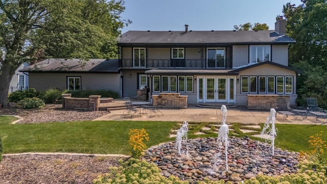 rear view of house featuring french doors, a patio, a balcony, and a lawn