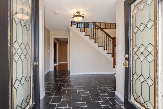 entrance foyer featuring stairway, baseboards, and stone finish flooring