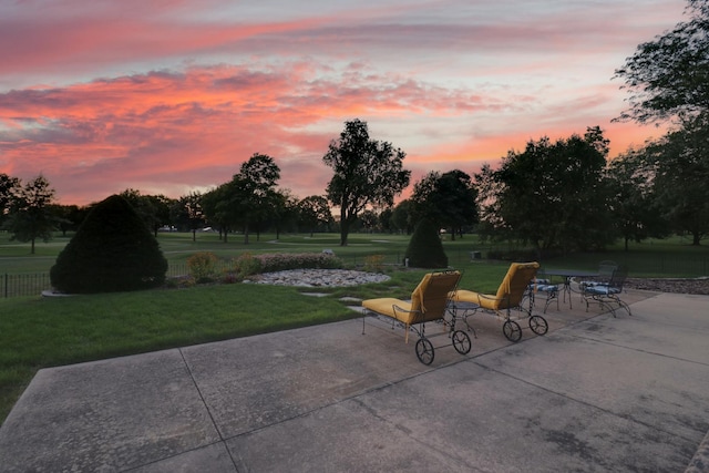 patio terrace at dusk featuring a lawn