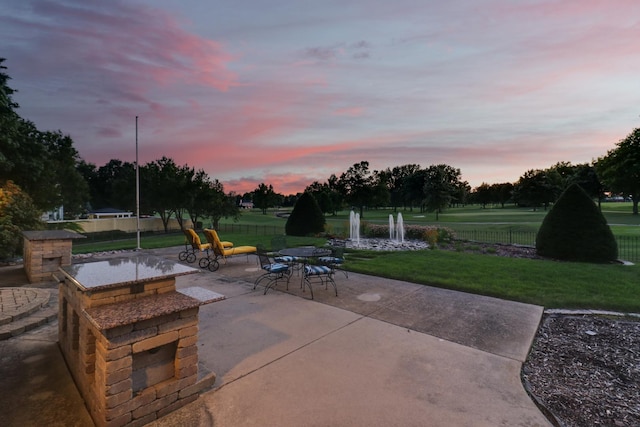 patio terrace at dusk featuring a yard