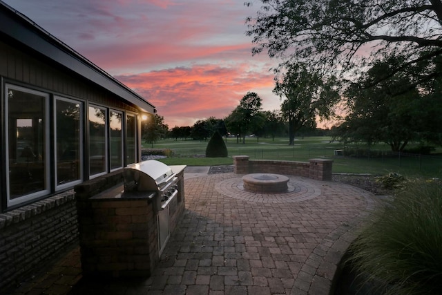 patio terrace at dusk featuring a fire pit, area for grilling, and a grill