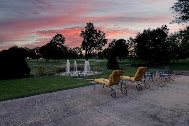 patio terrace at dusk featuring a lawn