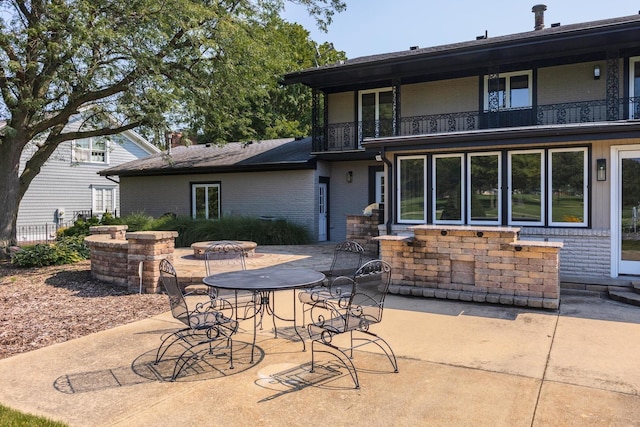 back of property with a patio, a balcony, and brick siding