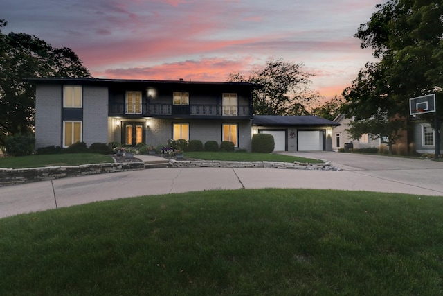 view of front of house featuring a garage, a balcony, and a yard