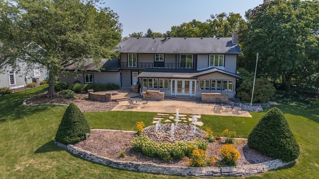 rear view of property with a lawn, a patio, a sunroom, a balcony, and a chimney