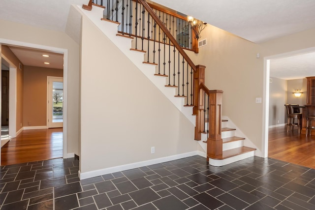 staircase with hardwood / wood-style floors and an inviting chandelier