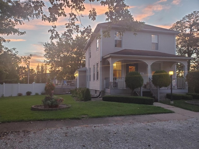 view of front of property featuring covered porch, a front lawn, and fence