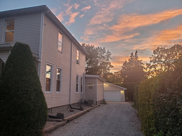 property exterior at dusk with an outbuilding, central AC, and a garage