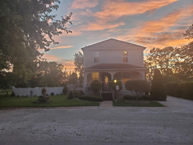 view of front of property with a porch, a lawn, and fence