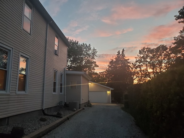 property exterior at dusk with a garage and an outbuilding