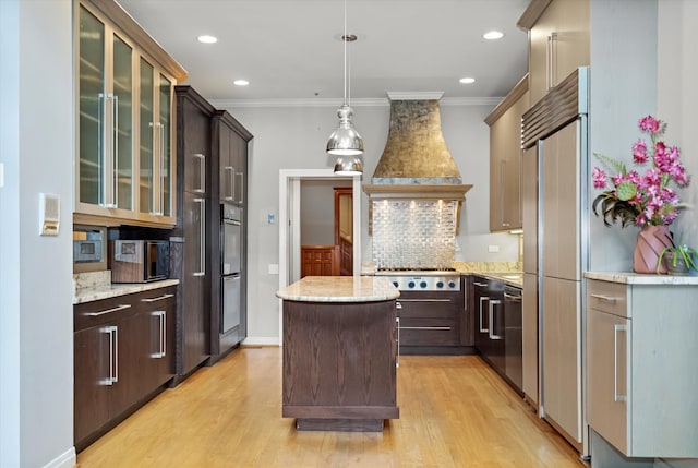 kitchen with a center island, appliances with stainless steel finishes, light hardwood / wood-style flooring, custom exhaust hood, and decorative backsplash