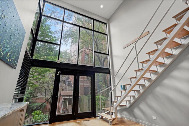 foyer with a towering ceiling, hardwood / wood-style floors, and french doors