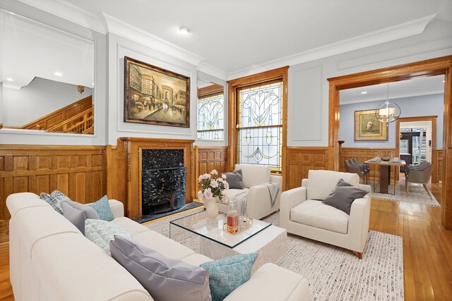 living room with a fireplace, a notable chandelier, light hardwood / wood-style floors, and ornamental molding