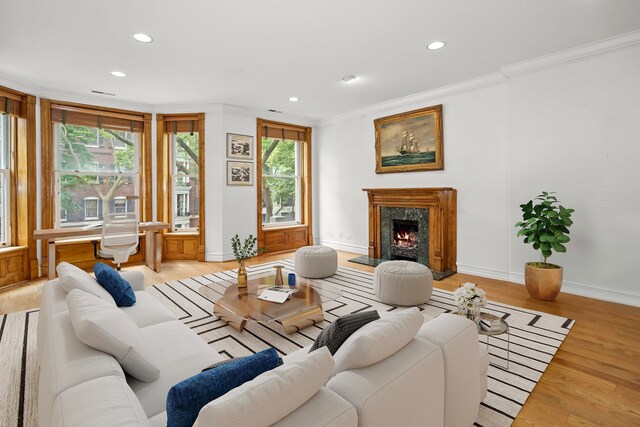 living room with a fireplace, crown molding, and light wood-type flooring