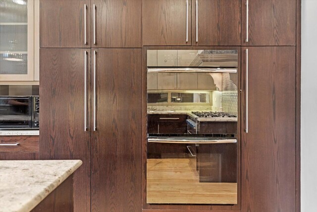 interior space with light stone counters, wall oven, and hardwood / wood-style flooring