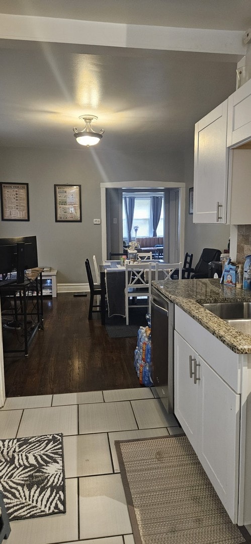 kitchen featuring hardwood / wood-style floors, light stone countertops, white cabinetry, and stainless steel dishwasher