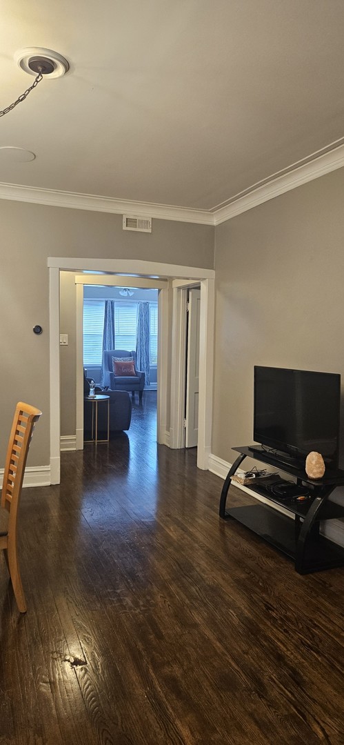 living room featuring dark wood-type flooring and ornamental molding