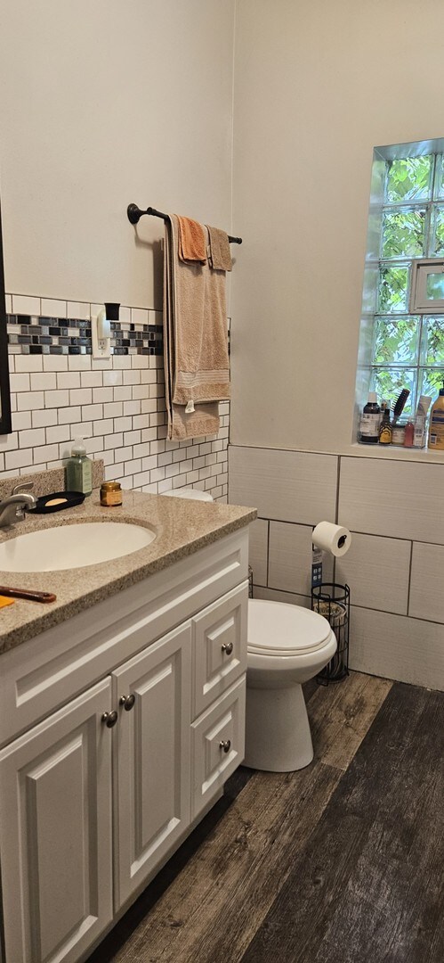 bathroom with vanity, toilet, hardwood / wood-style flooring, and decorative backsplash