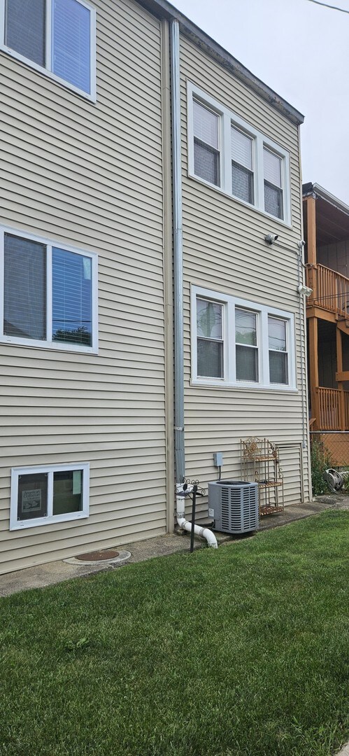 rear view of property with a balcony, a yard, and central air condition unit