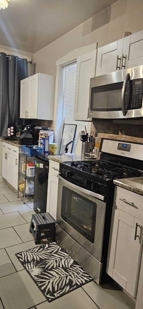 kitchen with stone counters, appliances with stainless steel finishes, white cabinetry, and tasteful backsplash