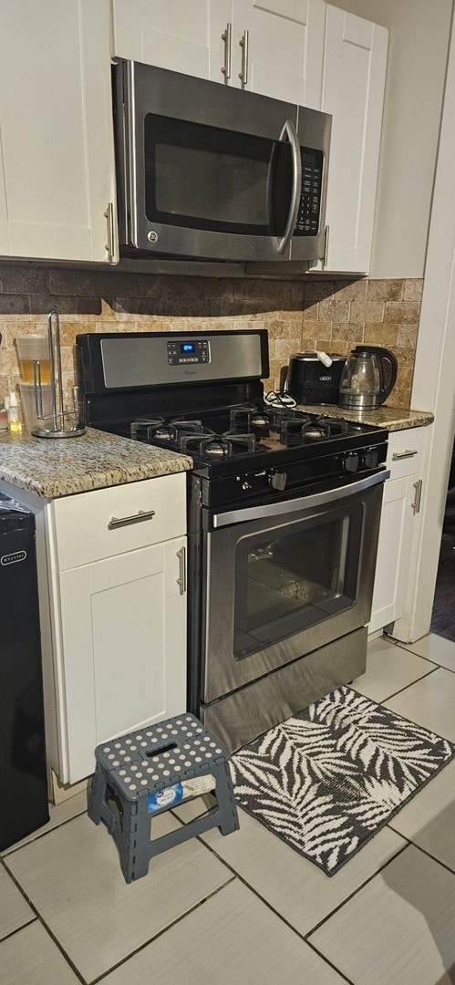 kitchen with appliances with stainless steel finishes, backsplash, and light tile patterned floors