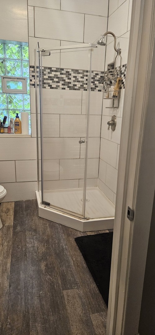 bathroom with hardwood / wood-style floors, toilet, and walk in shower